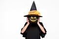 Young woman in witches hat and costume holding pumpkin in front of her face. Halloween Witch with scary face Jack o Lantern. Royalty Free Stock Photo