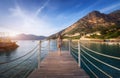 Young woman on wooden pier on sea shore is looking on mountain Royalty Free Stock Photo