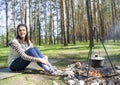 Young woman in the woods near the fire with a pot Royalty Free Stock Photo