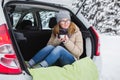 Young woman sits in the trunk of the car and holds a cup of hot tea Royalty Free Stock Photo