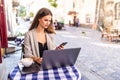 Young woman work on laptop and using phone sitting in street cafe Royalty Free Stock Photo