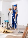 Young woman worker cleans in the room with a vacuum cleaner Royalty Free Stock Photo