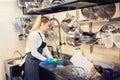 Young woman worker washing dishes using sponge in restaurant sink at end of working day Royalty Free Stock Photo