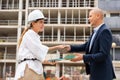 Young woman working as a process engineer, friendly shakes hands with a male customer