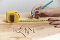 Young woman working in carpentry, marking measurements on a wooden strip with a pencil Royalty Free Stock Photo