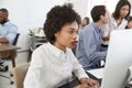 Young woman working at computer in a busy open plan office Royalty Free Stock Photo