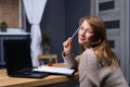 Young woman working at home. Blonde looking cute to the camera. White sheet folder for notice. Online study and learning Royalty Free Stock Photo