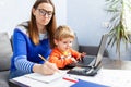 Young woman working at home with a laptop with a child on her lap Royalty Free Stock Photo