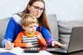 Young woman working at home with a laptop with a child on her lap Royalty Free Stock Photo