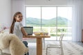 Young woman working from home office. Freelancer using laptop and the Internet for shopping online. Happy girl smiling Royalty Free Stock Photo