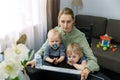 young woman working from home during the quarantine. using laptop at desk with kids on her lap Royalty Free Stock Photo