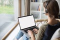 Young woman working at home. Student girl wearing headset using laptop computer with empty white blank screen. Royalty Free Stock Photo