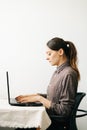 Young woman,working from home during virus quarantine,on her laptop.girl is sitting at white table,in minimalistic interior.cosy Royalty Free Stock Photo