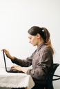 Young woman,working from home during virus quarantine,on her laptop.girl is sitting at white table,in minimalistic interior.cosy Royalty Free Stock Photo