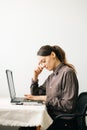 Young woman,working from home during virus quarantine,on her laptop.girl is sitting at white table,in minimalistic interior.cosy Royalty Free Stock Photo