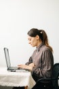 Young woman,working from home during virus quarantine,on her laptop.girl is sitting at white table,in minimalistic interior.cosy Royalty Free Stock Photo