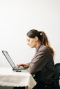 Young woman,working from home during virus quarantine,on her laptop.girl is sitting at white table,in minimalistic interior.cosy Royalty Free Stock Photo