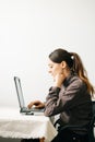 Young woman,working from home during virus quarantine,on her laptop.girl is sitting at white table,in minimalistic interior.cosy Royalty Free Stock Photo