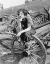 Young woman in working jeans sitting on wheel eating an apple