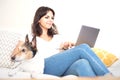 Young woman working on a laptop computer with little dog beside Royalty Free Stock Photo