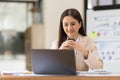 Young woman working on a laptop in the office. Asian businesswoman sitting at her workplace in the office. Beautiful Royalty Free Stock Photo