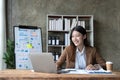 Young woman working on a laptop in the office. Asian businesswoman sitting at her workplace in the office. Beautiful Royalty Free Stock Photo