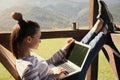 Young woman working with laptop on outdoor wooden terrace in mountains Royalty Free Stock Photo