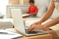 Young woman working on laptop while son drawing in living room, closeup. Home office concept Royalty Free Stock Photo