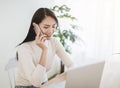 Young woman working on laptop and talking on the phone at home Royalty Free Stock Photo