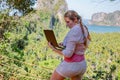 Young woman working with laptop on a top of the mountain with view on sea and tropical beach. Work and travel. On line business Royalty Free Stock Photo