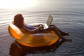 Young woman working on a laptop in the water on an inflatable ri Royalty Free Stock Photo