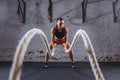 Young woman working out with battle ropes in cross fit gym Royalty Free Stock Photo