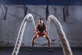 Young woman working out with battle ropes in cross fit gym Royalty Free Stock Photo