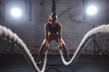 Young woman working out with battle ropes in cross fit gym Royalty Free Stock Photo