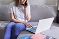 Young woman working remotely at home sitting on sofa with laptop Royalty Free Stock Photo