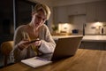 Young Woman Working Or Studying On Laptop At Home At Night Taking Picture Of Notes With Mobile Phone Royalty Free Stock Photo