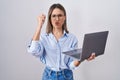 Young woman working using computer laptop angry and mad raising fist frustrated and furious while shouting with anger Royalty Free Stock Photo