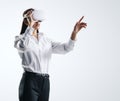 Young woman working in virtual reality environment in VR glasses, presses by her finger on virtual interface on abstract light