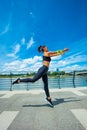 young woman workout on strainght and muscular build jumping outdoor in the city promenade by the river Royalty Free Stock Photo