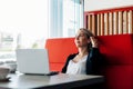 A young woman works in a cafe for a cup of coffee, uses a laptop, pauses. Business concept Royalty Free Stock Photo