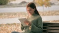 Young woman works on the tablet in the park on a bench. A girl using a digital tablet prints messages on a city street Royalty Free Stock Photo