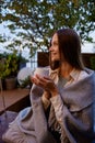 Young woman wrapped in warm blanket in cozy place