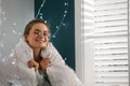 Young woman wrapped in warm blanket at home