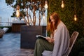 Young woman wrapped in warm blanket reading book in cozy place