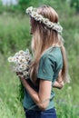 Young woman with a wreath of daisies on her head in the sun on a field of grass Royalty Free Stock Photo