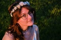 Young woman with a wreath of white flowers in the sunset. A girl in a white dress who looks like a fantasy character