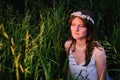 A young woman with a wreath of white flowers in the tall grass and reeds. A girl in a white dress who looks like a mermaid from a Royalty Free Stock Photo