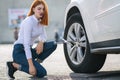 Young woman with wrench changing wheel on a broken car Royalty Free Stock Photo