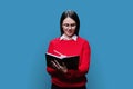 Young woman writes in business diary, on blue studio background. Royalty Free Stock Photo