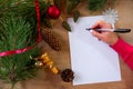 Young woman writes a New Year's greeting card or Christmas wish sheet on a white piece of paper Royalty Free Stock Photo